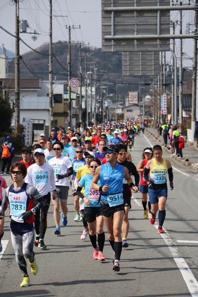 まっすぐに伸びた道路をサングラスをかけたランナー達が走っている写真
