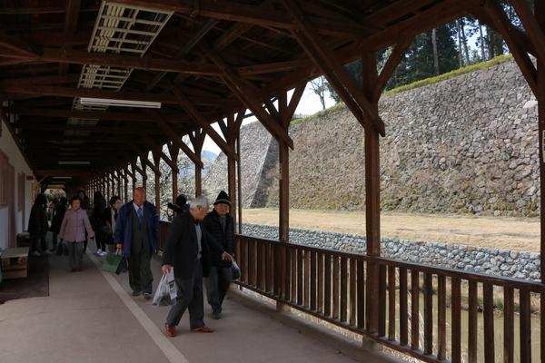 木造の天井がある廊下を見学の人達が歩いている写真