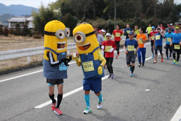 ミニヨンの着ぐるみ姿の男性ランナー2人が紙コップを持って走っている写真