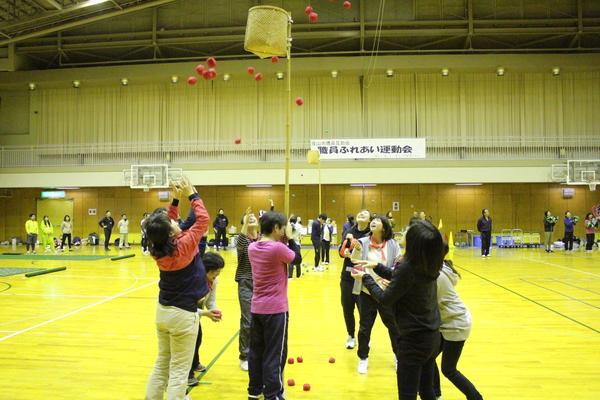 女性の職員の方達が参加しており、竹の上に付けられた籠に向かって赤い球を投げている玉入れの競技を写している写真