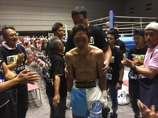 試合が終わりリングを後にする角谷選手と選手に拍手をしている関係者の方々の写真