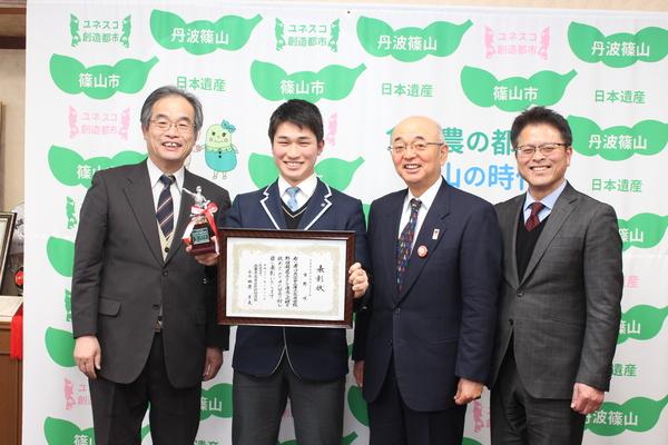 市野 咲(いちの しょう)君が賞状とトロフィーを持って、市長と関係者で記念写真