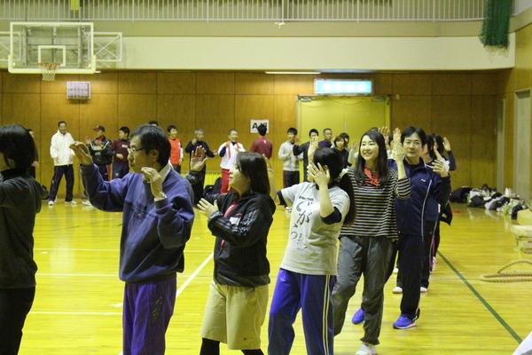 体育館の中に大きな円を作って踊りを踊っている様子の写真