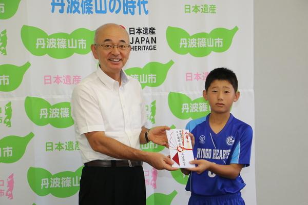 市長とキャプテンの水谷君が祝い金を持ち記念写真