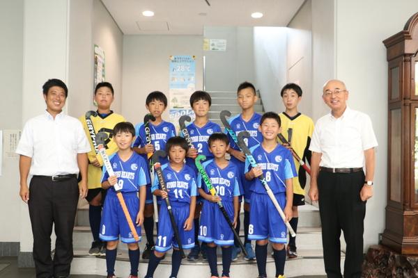 ユニフォーム姿の小学生ホッケーチームと市長で集合写真