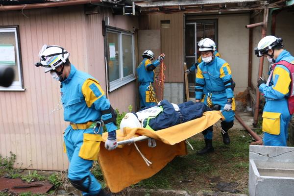 警察の方がケガをした方をタンカーに乗せて運んでいる写真