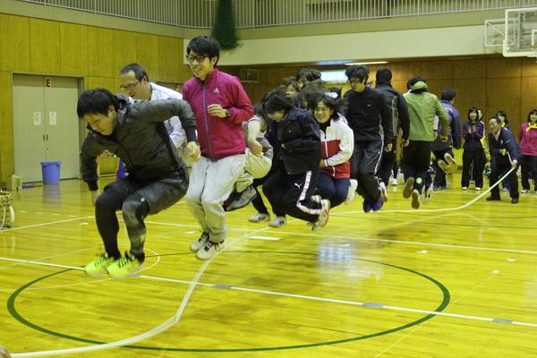 大縄跳びで10人以上の職員が大きくジャンプしている写真