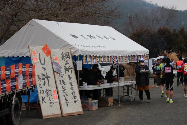 しし汁が配布されているテント前で女性の方がしし汁を手渡している写真