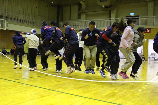 大縄跳びで、窮屈に重なり合ってジャンプしている職員の写真