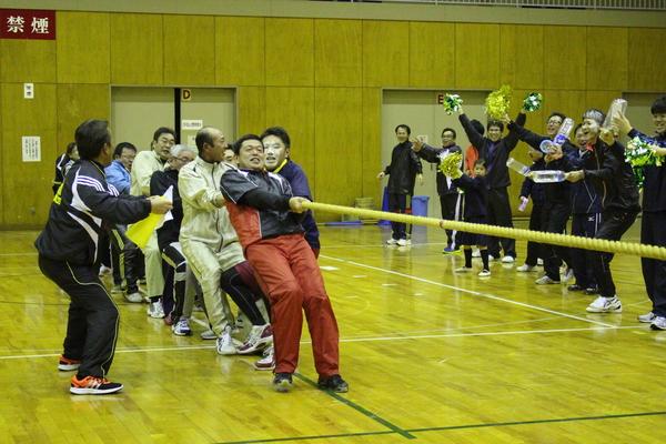 綱引きを頑張る方と賑やかな応援団の写真