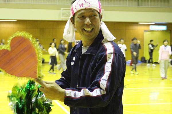 ハチマキとハートのプラカードを持ってニッコリ笑顔の男性の写真