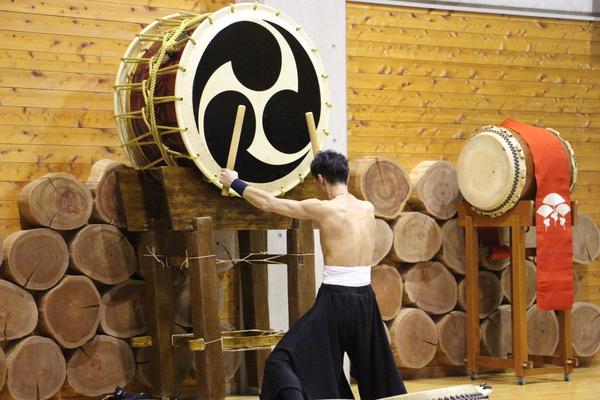 大きな和太鼓を叩いている男性の後姿の写真