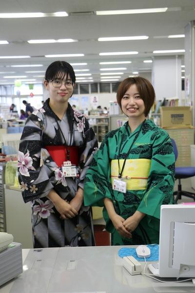 涼しげな浴衣姿の女性職員2名が笑顔で窓口で並んで写っている写真