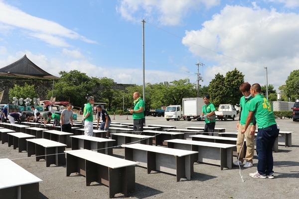 お祭り会場の椅子をロープできれいに計りながら男性らが並べている様子