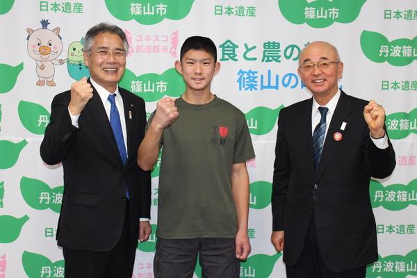 教育長と俣野君と市長がガッツポーズをして笑顔で写っている写真