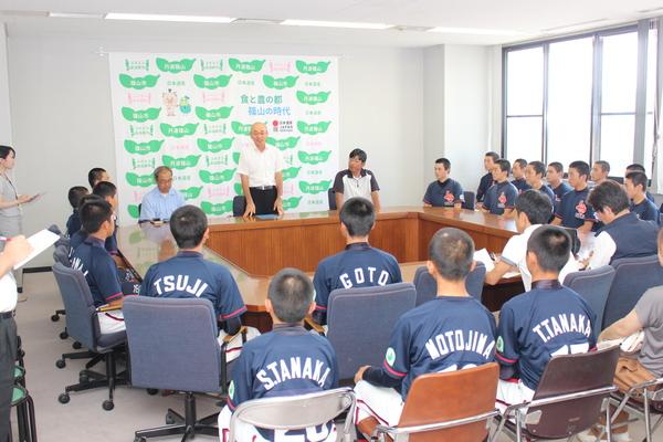 ユニフォームを着た男子生徒たちが注目する中、市長が立って話をしている写真