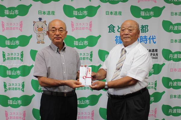 市長と井関 道夫さんが一緒に、祝儀袋を持っている写真