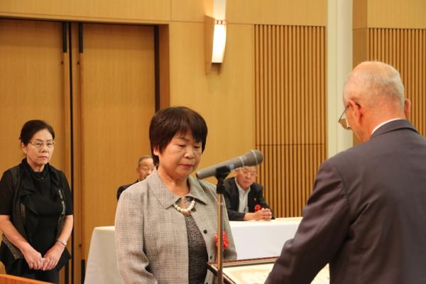 賞状を読み上げる市長の向かい側に立っている女性受賞者を市長の後方から撮った写真