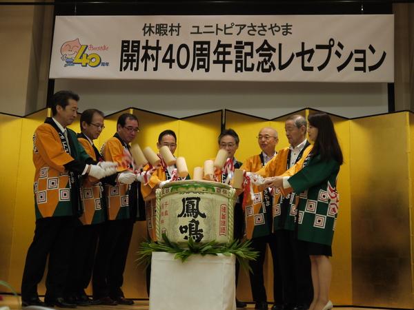舞台に用意されている祝い樽を法被を着た方達でいっせいに蓋を叩いている写真