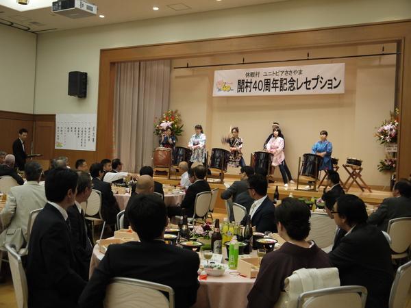 舞台の上で法被を着た4人の女性が大きな太鼓を叩いている写真