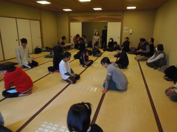 畳の上に、2名で1組で向かい合って座る、かるた大会の参加者の写真