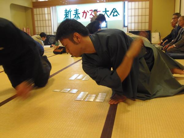 かるたの札を弾いた袴姿の男性の写真