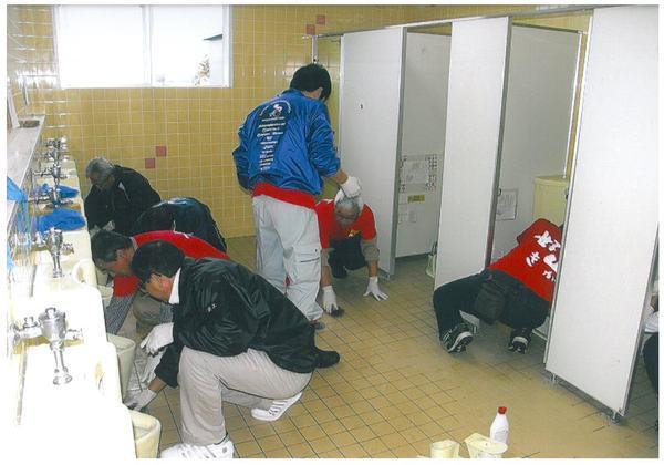 参加者の男性達がトイレの床を磨いている様子の写真