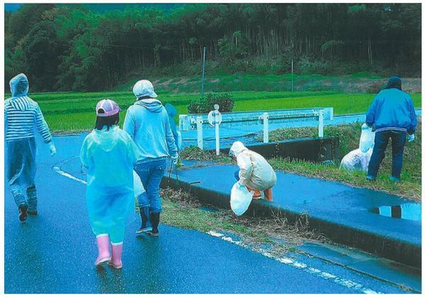 カッパを着た参加者達が道路のゴミを見つけて拾っている様子の写真