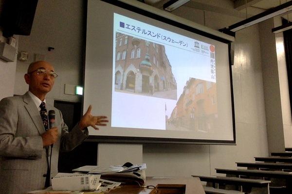 スクリーンの横で市長がマイクを持ち話をしている写真