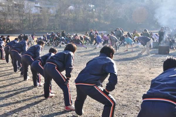 ジャージを着た学生が、走る前の準備体操をするのを後ろから見た写真