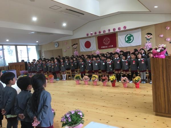 胸に花をつけた卒業生の子供たち全員が横3列に並び、在園生たちと向かい合っている写真