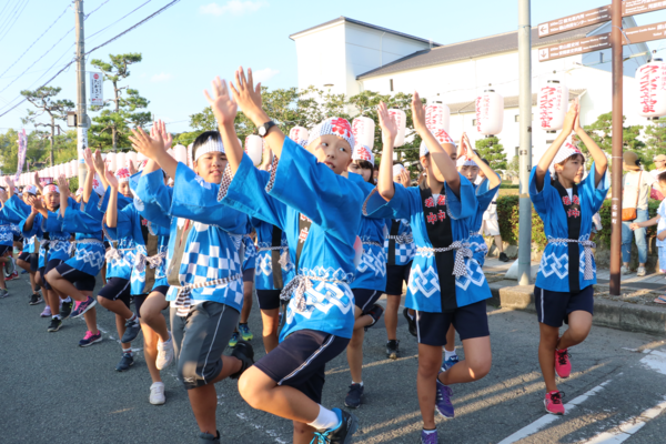 お祭りの法被を着た子供達が両手を上げ元気いっぱい踊っている写真