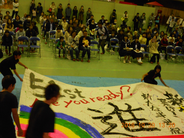 書道パフォーマンスで子供達がみんなで大きな布を広げている写真