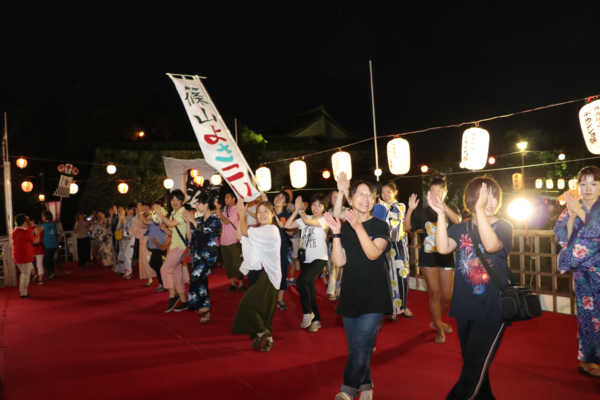 赤いカーペットの上で沢山の女性たちが踊っている写真