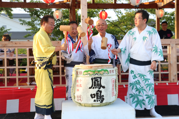 浴衣を着た男性3人と市長が木製のハンマーを手に持ちお祝いで酒樽のフタを木槌で叩き割る