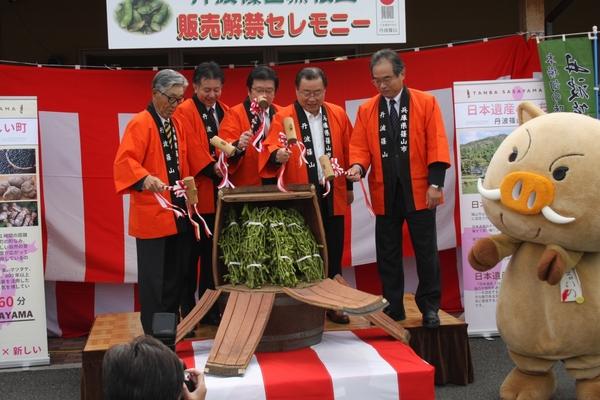 5人の法被を着た男性達が木槌を持っていて、中央には樽に入った枝豆が置かれている写真