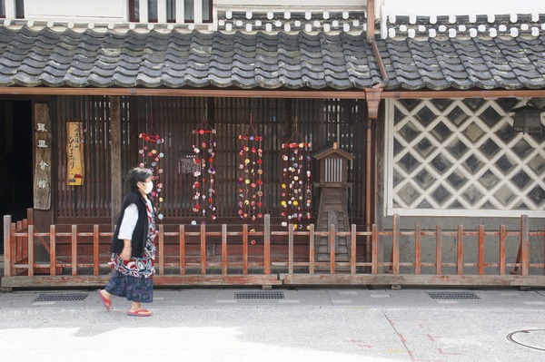河原町でのひな祭りに飾られた建物の前を一名の女性が歩く写真