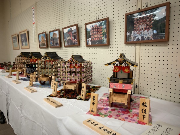 机の上に飾られた山鉾の模型と実際の写真が展示している様子