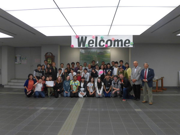 市民ホールでワラワラ市から来られた方々と市職員がウェルカムと書かれたボードの下で並んでいる写真