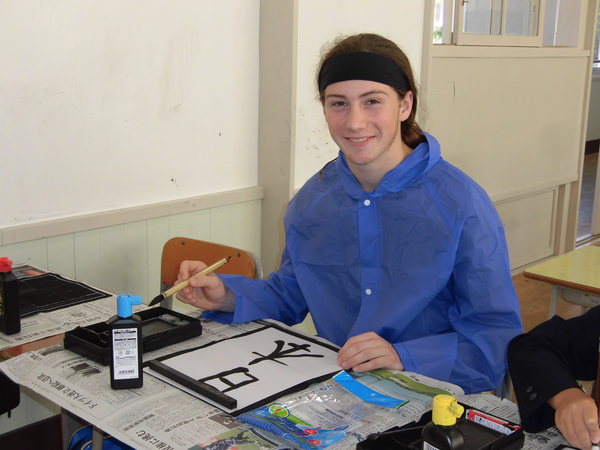 ワラワラ市から来られた方が習字に挑戦し、日本と書き終え筆を持ちながら笑っている写真