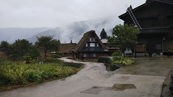 背景に美しい山と合掌づくりの雨上がりの写真