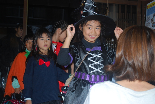 ハロウィーン衣装を着た女の子が帽子をもって笑っていたり、列を作ってならんでいる様子