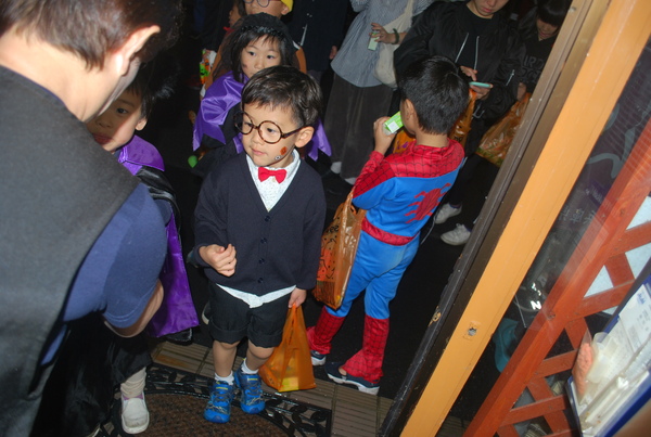 顔にペイントした男の子やハロウィーン衣装の女の子が大人を見つめる様子