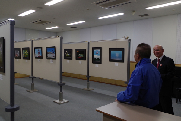 展示されている写真や作品を前に談笑する男性と市長の写真