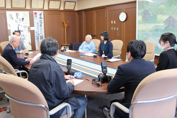 応接室の大きな机に寄付者の藤木さんを取り囲み市長と記者、カメラマンの方々が座られている写真
