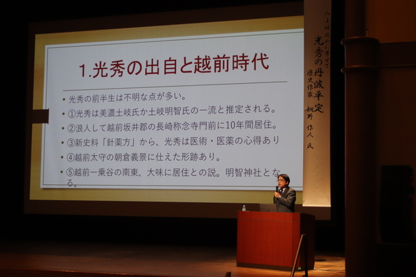 光秀と波多野兄弟についてスクリーンを前にマイクを持ち舞台上で話されている桐野作人先生