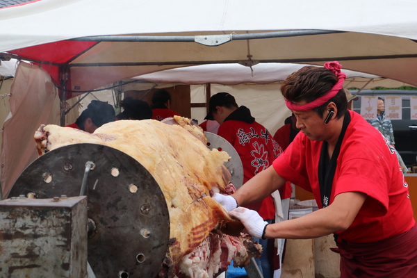 大型機械にセットされた牛肉をさばく様子の赤い鉢巻をした男性
