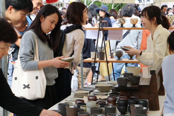 丹波焼の商品を手に取って吟味する女性客や女性店員と楽しく会話している女性客の様子