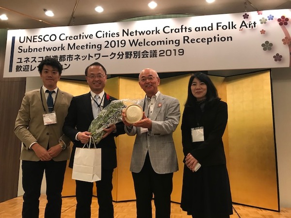 会議場の金屏風の前で市長と市職員が山野市長を挟んで笑顔で立っている写真