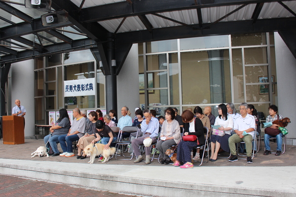 表彰される長寿犬と飼い主の方々が椅子に座っている写真